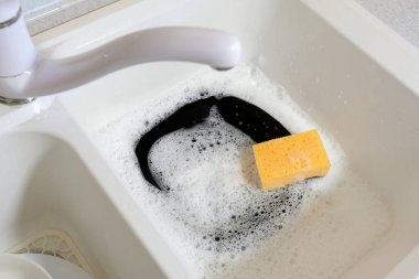 Sünger ve kirli bulaşıklar lavaboda. Mutfakta ödev var..