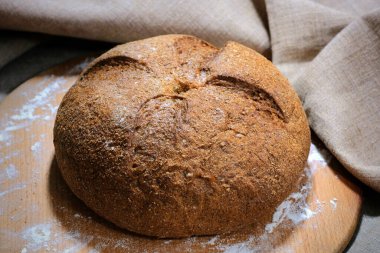 Koyu bir mutfak masasında taze pişmiş çavdar ekmeğinin yan görüntüsü..
