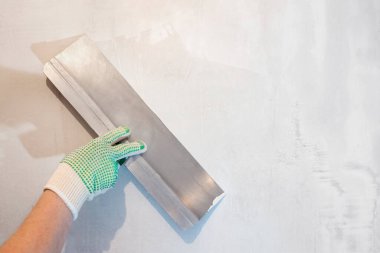 Spatula tutan bir el. Aletler, alçı duvar..