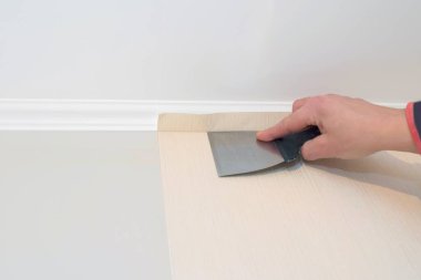 İşçi tamir sırasında duvarda bir spatula ile duvar kağıdını düzleştirir. Onarım kavramı.