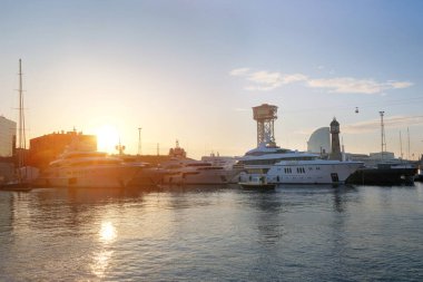 Günbatımında modern yatlar limana demirlemiş. Şehir manzarası.