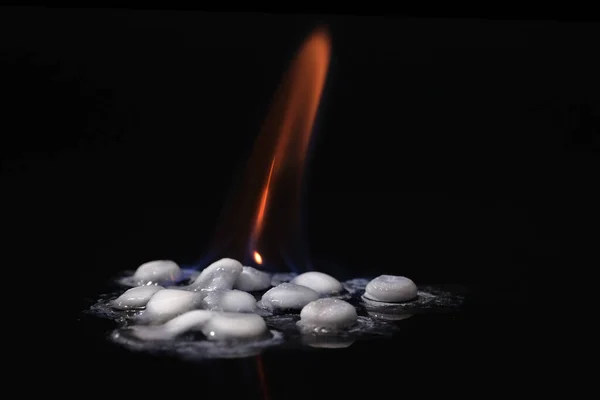 Stop addiction. White pills on fire on a black background. Drug Abuse Concept.