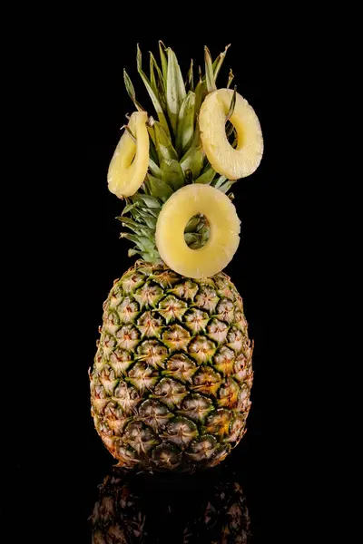 Pineapple and pineapple slices on a black background. Round slices of pineapple on green leaves.