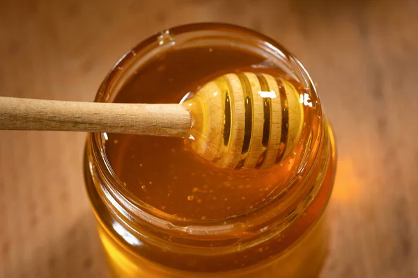 Ένα Γυάλινο Βάζο Αρωματικό Μέλι Και Μια Ξύλινη Κουτάλα Μελιού — Φωτογραφία Αρχείου