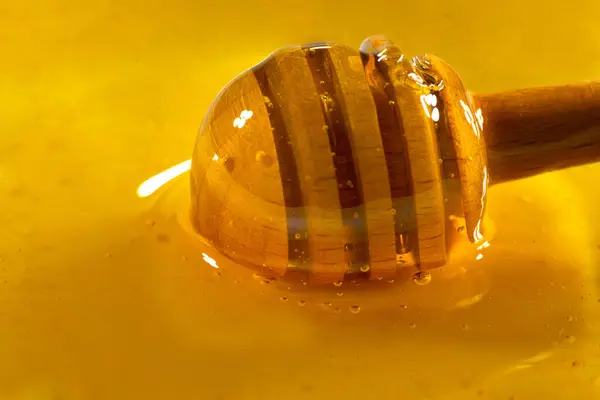 蜂蜜の木のボウルに蜂蜜のディップから滴り落ちる 接近中だ 健康的な有機厚さの蜂蜜は 木製の蜂蜜のスプーンから浸漬 クローズアップ — ストック写真