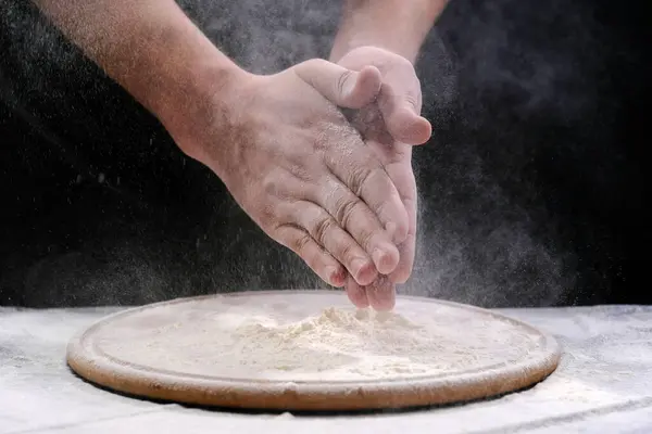 Chef hand clap with splash of white flour on black background. Hands in flour.