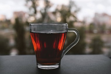 Soğuk bir sonbahar gününde bir fincan sıcak çay pencerenin yanında durur..