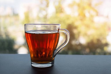 Pencerede bir fincan çay var. Sabah çayı. Pencerenin arka planında çay partisi.