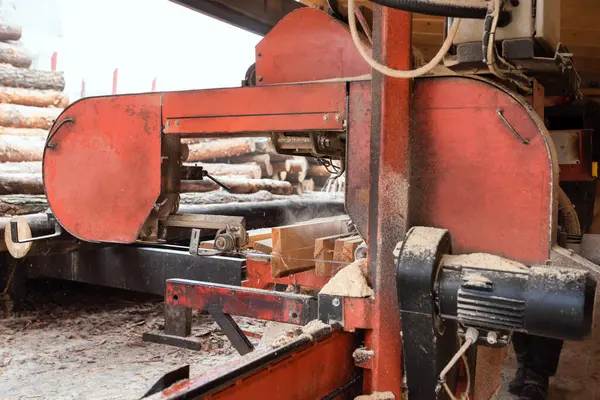 製材所で木製板を加工する 製材所の装置のログを処理する過程で 木のトランクはプランクに切断されます 木材生産工場のウィングマシン — ストック写真