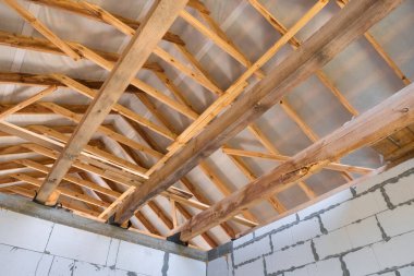 Yeni sürdürülebilir bir ev inşaatında duvarlar ve kirişler için tahta kalaslar. Bitmemiş tuğla bina geliştirme aşamasında.