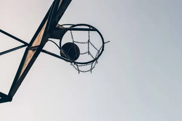 Silhouette of a basketball ball passing a basket on a sky background. Sports lifestyle concept