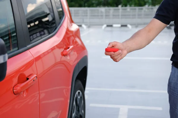 一名男子用遥控钥匙打开停在停车场内的汽车的手 遥控和车辆保护概念 — 图库照片