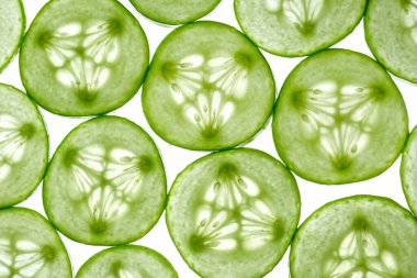 Beyaz arka planda izole edilmiş taze kesilmiş salatalık dilimleri. Salatalık ışıkta dilimler. Üst görünüm.