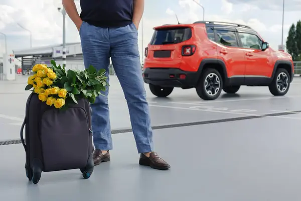在外面的停车场里看到提着行李和鲜花的人 — 图库照片