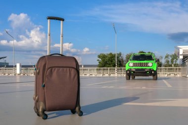 Açık bir otoparktaki arabanın arka planındaki bavul. Tatil kavramı.