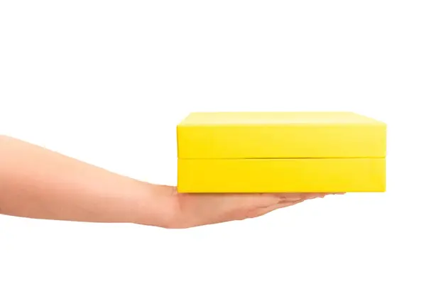 白い背景に隔離された黄色いギフト用の箱を握る手 サイドビュー — ストック写真