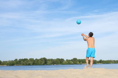 Güneşli bir günde plaj voleybolu oynayan bir adam. Arkadan bak. Spor yaşam tarzı..