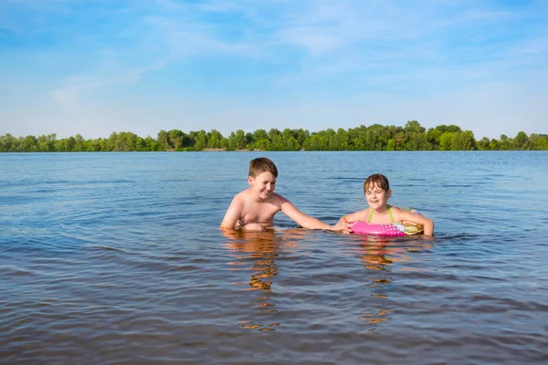 Happy boy and girl play in the water. Summer holidays. Children have fun outdoors.