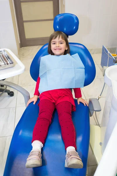 A child patient is sitting in a dental chair.