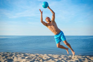 Güneşli bir günde deniz kenarında voleybol oynayan bir plaj oyuncusu. Konsept sağlıklı bir yaşam tarzı..