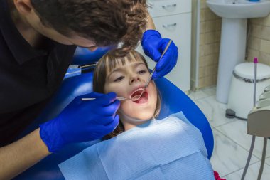 Klinikte küçük kız dişlerini muayene eden bir diş hekimi. Tıp, dişçilik ve sağlık hizmetleri kavramı.