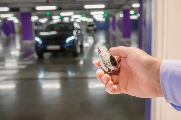 地下駐車場の車の背景に対する手のキー クローズアップ — ストック写真