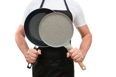 Siyah önlüklü bir adamın gövdesi ellerinde kızartma tavalarıyla beyaz izole bir arka planda. Yemek pişirme kavramı.