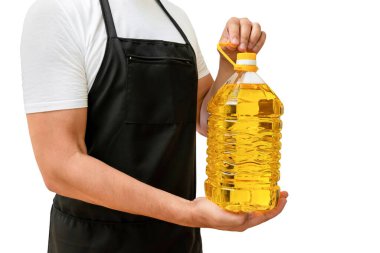A bottle of sunflower oil in the hands of a cook on a white isolated background. The concept of cooking. clipart