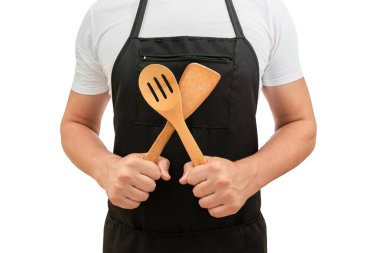 Şefin gövdesi siyah bir önlükteydi. Mutfak ahşap kaşıklarıyla izole edilmiş beyaz bir arka plan. Yemek pişirme konsepti.
