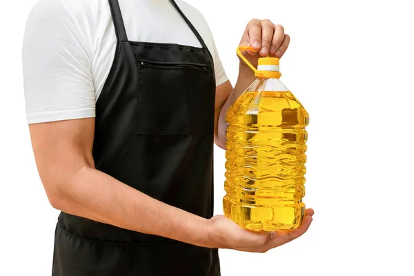 Beyaz izole bir arka planda bir aşçının elinde bir şişe ayçiçeği yağı. Yemek pişirme kavramı.