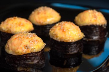 Siyah arka planda peynirli fırında suşi ruloları..