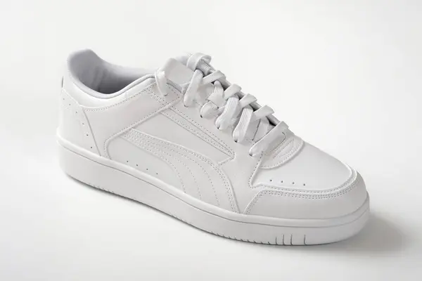 One white sneaker on a white background. Light shoes close-up