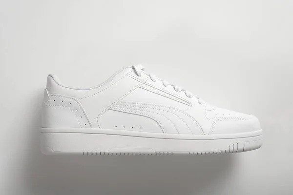 White sneaker on a white background with a shadow. Light shoes close-up
