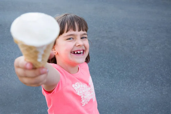 Happy little girl with ice cream in her hand outdoors.