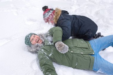 Mutlu bir baba ve çocuk sırtında kar ile oynuyorlar. Kardaki insanlar.