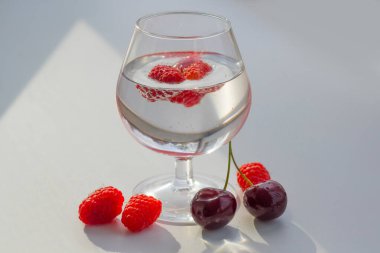 Masanın üzerinde bir bardak Champaign olan güzel meyveler. Ahududu ve kiraz.