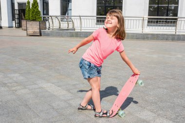 Küçük çocuk güneşli bir günde kaykay sürmeyi öğreniyor. Konsept aktif bir yaşam tarzı..