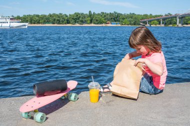 Bakkal çantasıyla gezinen küçük bir çocuk. Güneşli yaz günü, fast food.