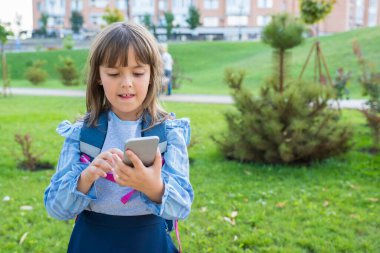 Okul üniformalı bir kız parkta telefon kullanıyor..