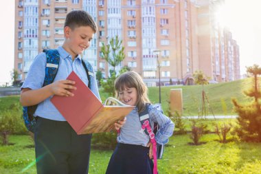 Okul üniformalı ve parkta kitabı olan mutlu çocuklar. Okul yılının başında..