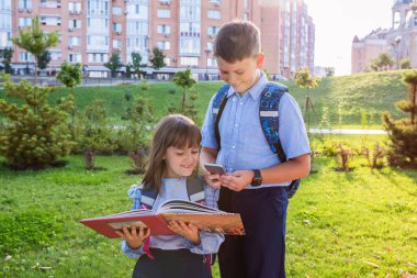 Okul üniformalı ve parkta kitabı olan mutlu çocuklar. Okul yılının başında..