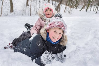 Mutlu çocuklar kışın açık havada kar yığınında oynarken eğlenirler..