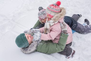 Babalarıyla kış kıyafetleri içinde çocuklar, sokakta kar yığınında oynuyorlar. Mutlu aile kışın dışarıda vakit geçirir..