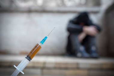 Uyuşturucu madde içeren bir şırınga, uzun süreli uyuşturucu kullanımından sonra depresyon geçiren bir bağımlının arka planına karşı. Yaşam biçimi.