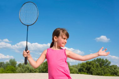 Elinde raketle plaj badmintonu oynayan 7-8 yaşlarında bir kızın portresi. Tatil sporları, tatil, spor, yaşam tarzı.