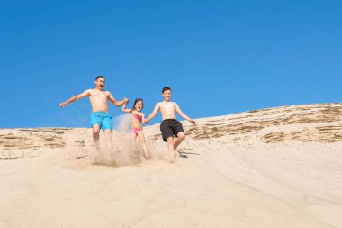 Kumsaldaki mutlu aile kumsalda koşuyor. Plaj tatilindeki aile, sağlıklı yaşam tarzı, tatil, tatil.