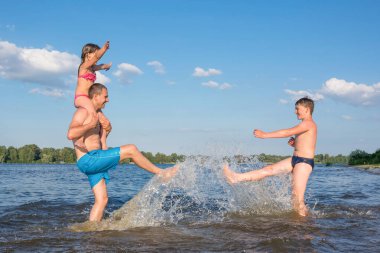Mutlu aile suda oynuyorlar. Aile tatili aktif tatil, spor, yaşam tarzı, hafta sonu konsepti.