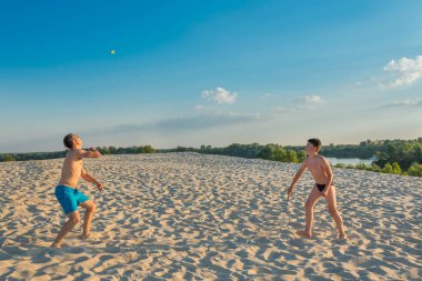 Spor ve sağlıklı yaşam tarzı kavramı. Baba oğul plaj badmintonu oynuyorlar. Aile yaz tatili.