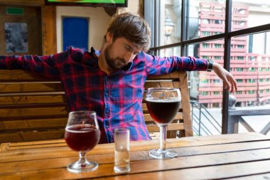 Depresyonda olan genç bir adam barda yalnız oturuyor. Sosyal bir sorun. Alkolizm kavramı, alkol bağımlılığıyla mücadele, kriz, depresyon