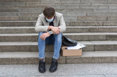 İşsizlik ve işten çıkarma kavramı. Merdivenlerde oturan bir şirket çalışanını kovmuş ve ağır depresyon geçirmiş. Ekonomik işsizlik krizi, bir salgın sırasında işten atılma